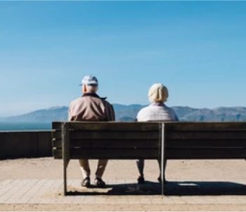 Elderly Couple Sitting On A Bench Enjoying The View
